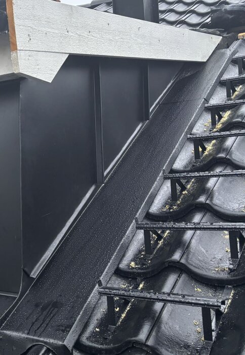 Takområde runt en kupa med plåtarbete och svarta takpannor, frågor kring effektiviteten mot väta samt synliga takstegar.