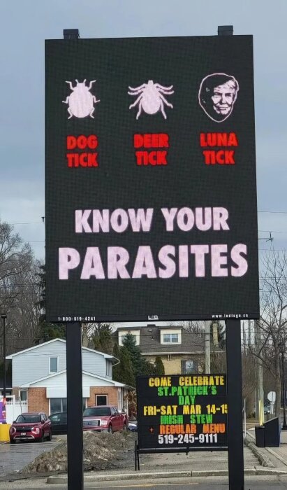 Elektronisk skylt med texten "Know Your Parasites" och tre fästingar: hund, hjort och en tecknad fästing märkt "Luna".