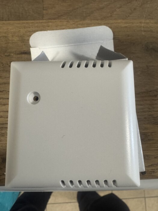 En vit innegivare placerad på ett träbord, delvis ur förpackningen.