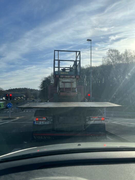 En lastbil med registreringsskylten "MR LIFT" står vid en vägkorsning under klar himmel.