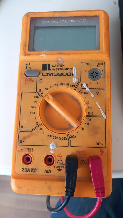 Orange multimeter CM3900 inställd på Ohm-läge med mätkablar anslutna.