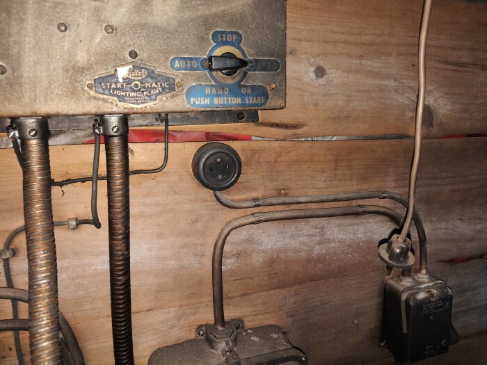 Vintage startpanel för belysningssystem med ledningar och en gammaldags strömbrytare på trävägg.