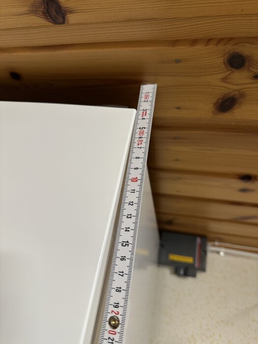 Överskåp med måttband visar 3 cm avstånd till taket i tvättstuga med trätak.
