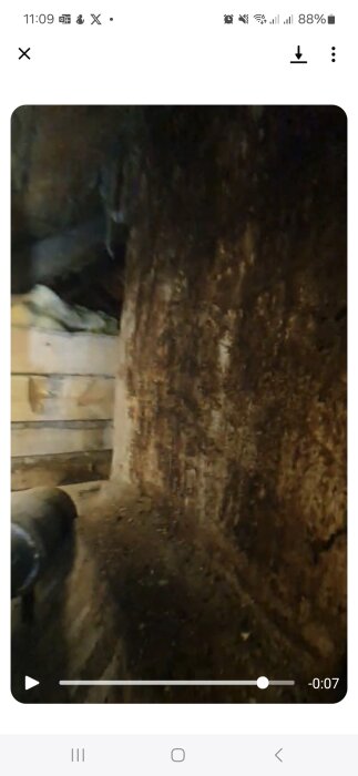 Missfärgad murstock på vinden med misstänkt musbajs vid basen, potentiellt orsakad av vattenläckage från taket.