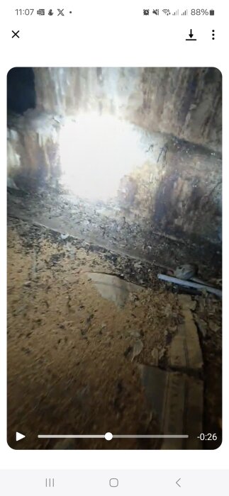 Missfärgad murstock på vinden med skräp och eventuella djurspår vid basen, fotograferad under en bygginspektion.