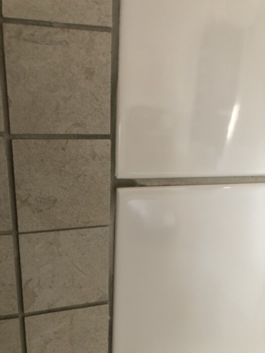 Fläckiga fogar mellan kakelplattor, med missfärgningar som ser blöta ut men är torra.