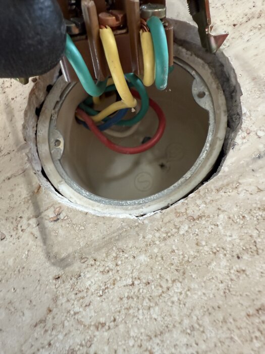 Närbild av en gammal brytare med färgade kablar kopplade i ett eluttag, visas i en diskussion om att byta eller koppla om den.