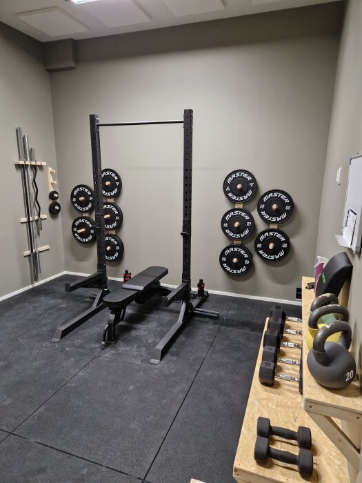 Hemmagym med träningsbänk, vikter och kettlebells, färdigt och redo för användning.