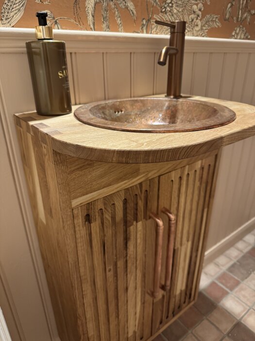 Handgjort trätoalettskåp med kopparhandtag och matchande kopparhandfat, oinmålat för naturlig finish.