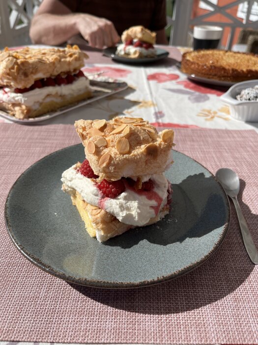 Pinocchiotårta med grädde och bär på en tallrik, serverad på en dukad balkong i solen, redo att avnjutas.