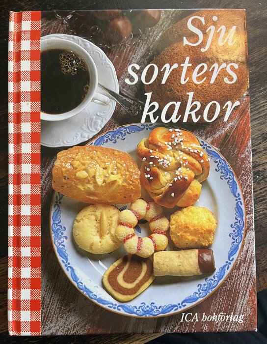 Omslag av "Sju sorters kakor" visar olika bakverk på en tallrik med en kopp kaffe.