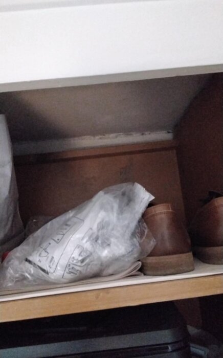 En hylla med ett mellanrum till väggen, full med saker inklusive en påse och skor.