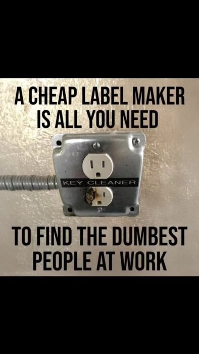 Rostig väggkontakt märkt "KEY CLEANER" med texten "A CHEAP LABEL MAKER IS ALL YOU NEED TO FIND THE DUMBEST PEOPLE AT WORK" ovanför och under.
