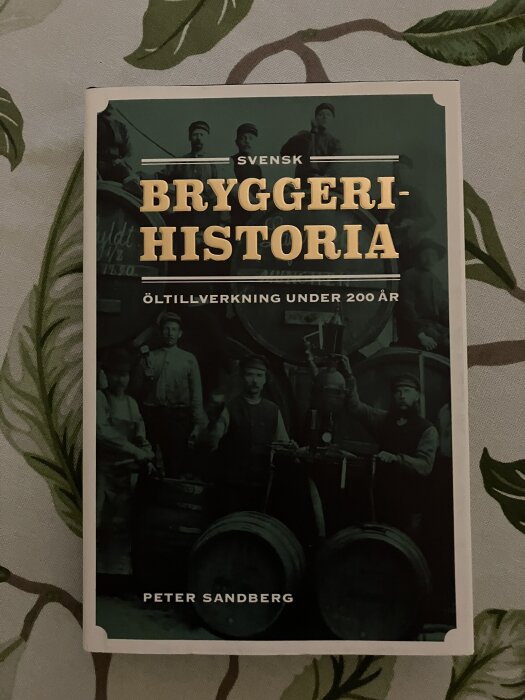 Bokomslaget till "Svensk bryggeri-historia" av Peter Sandberg, visar personer framför bryggutrustning med texten "Öltillverkning under 200 år".