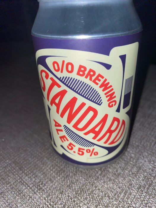 En burk med etiketten "Standard Ale 5.5%" från 0/0 Brewing, stående på en yta.