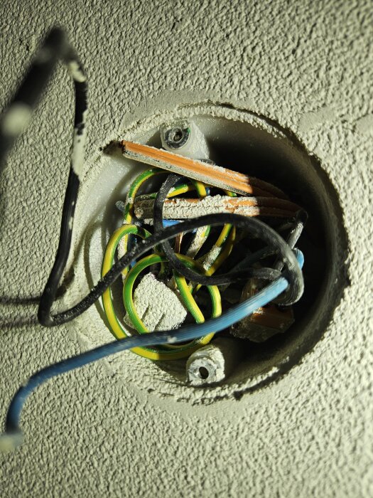 Elektrisk kopplingsbox i tak med exponerade kablar och gänga, omgiven av damm och puts från målningen, problem vid installation av lamputtag.