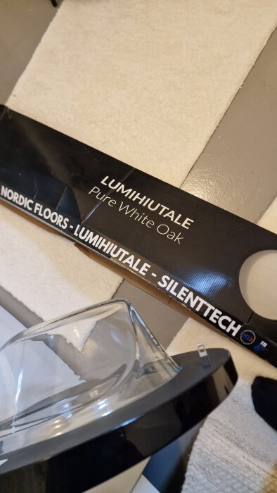 Förpackning med vinylgolv "LUMIHIUTALE Pure White Oak" från Nordic Floors på en ljus yta.