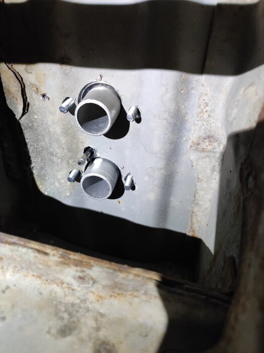 Två silverfärgade rör på en äldre motor utan oljeläckage, fotade under installation av värmare i en 20 år gammal campingbuss.