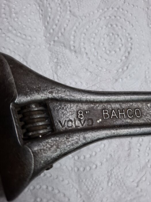 Skiftnyckel av märket Bahco med Volvos logotyp, sedd på en mönstrad vit bakgrund.