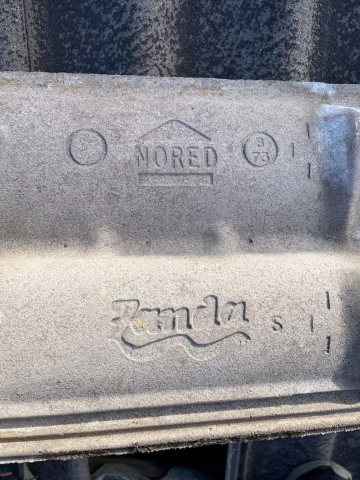 Takpanna med märkning "Zanda" och "NORED", med symboler som inkluderar siffror och bokstäver.