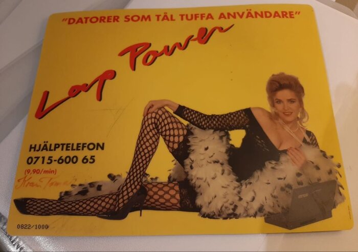 Reklamaffisch för datorer med en kvinna klädd i svart nätklänning och fjäderboa, liggandes bredvid en bärbar dator, texten "Datorer som tål tuffa användare".