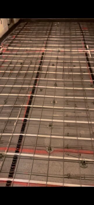 Värmegolv under installation med synliga slangar och metallnät.