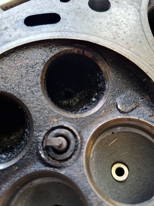 Närbild av motorcylinderhuvud med tydliga avgasventiler, delvis täckta av sotavlagringar.
