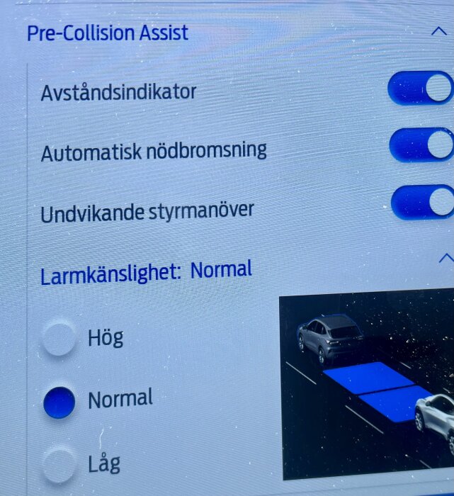 Bild av bilens Pre-Collision Assist-inställningar inklusive avståndsindikator, automatisk nödbromsning och undvikande styrmanöver, alla aktiverade.