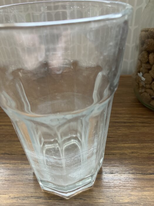 Ett tomt glas med kalkavlagringar på insidan, placerat på en träyta.