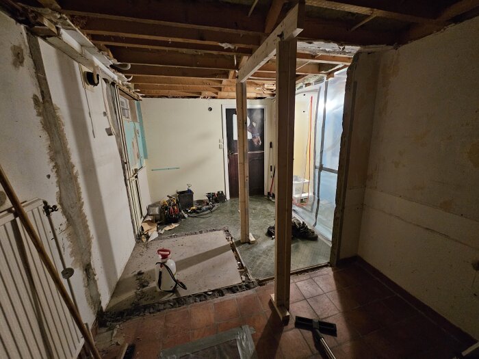 Ett rum med synliga reglar och verktyg på golvet under renovering, förberett för bilning.