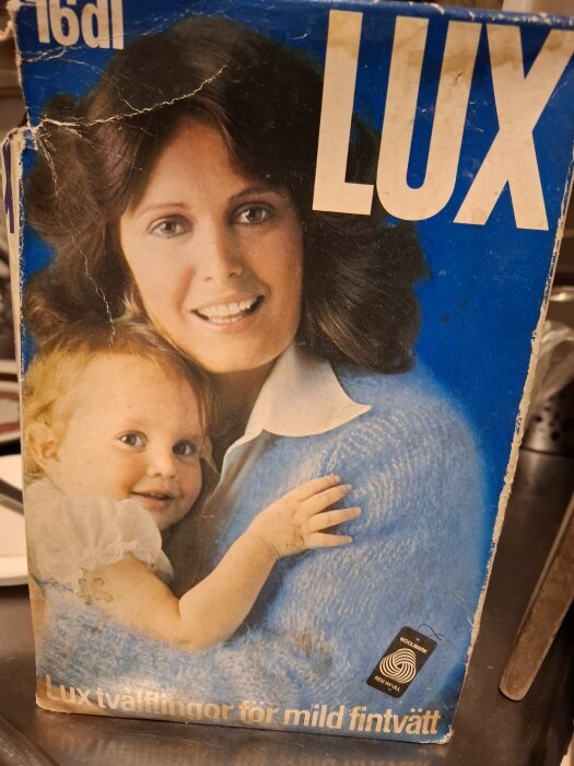 Förpackning av Lux tvåflingor med bild på leende kvinna och barn mot blå bakgrund.
