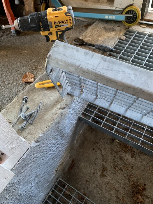 Metalltrappa sedd underifrån med verktyg och skruvar bredvid.