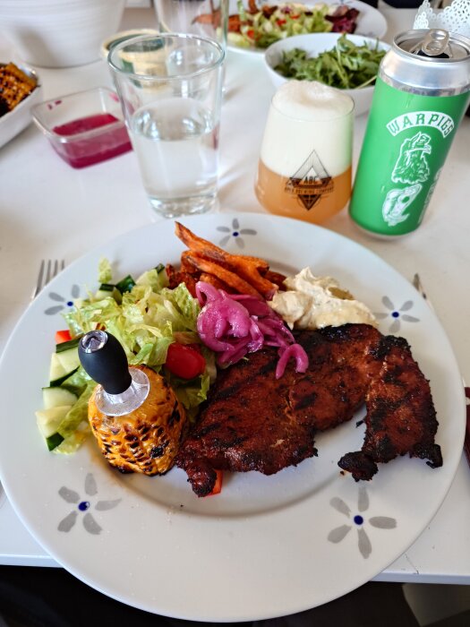 Grillad karré med sötpotatis, sallad, picklad lök, majs och bearnaisesås på en tallrik.