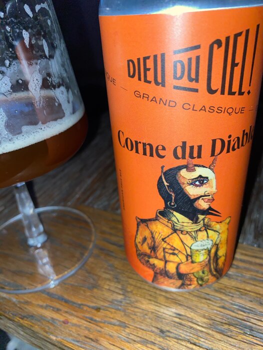Orange burk med "Dieu du Ciel! Corne du Diable" och glas med öl bredvid.