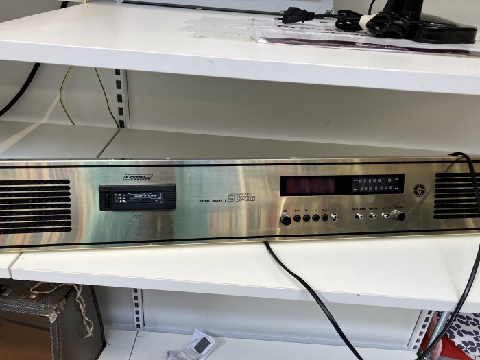 Radio- och kassettdäck i metallmonterat på hylla, del av projekt för att integrera stereo i sänggaveln.