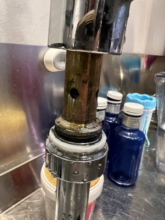 Närbild av en köksblandare med synliga gummipackningar, en vit och en svart, som verkar behöva bytas ut.