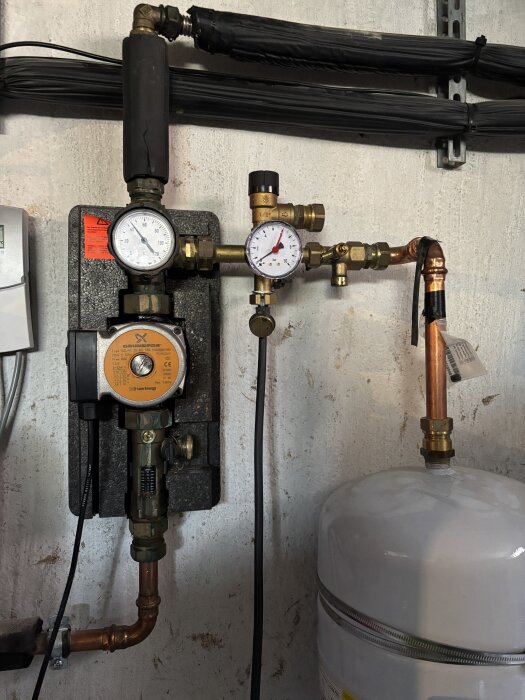 VVS-installation med två tryckmätare, en svart slang och en vit trycktank. Diskuteras påfyllning och rekommenderat tryck.