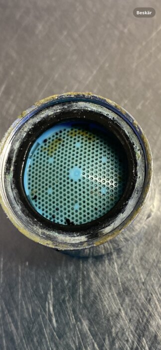 Kalkbelagd kökskransil av metall, med smuts och avlagringar, avsedd att skruvas av för rengöring.