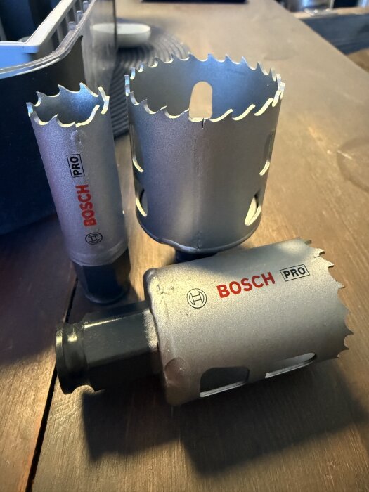 Tre Bosch hålsågar med ojämnt tandsnitt och synliga svetsfogar, placerade på ett träbord.