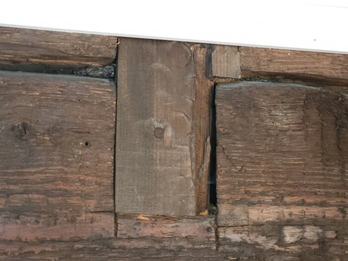 Spricka i gammal träpanel, möjlig plats för lindrevstätning.