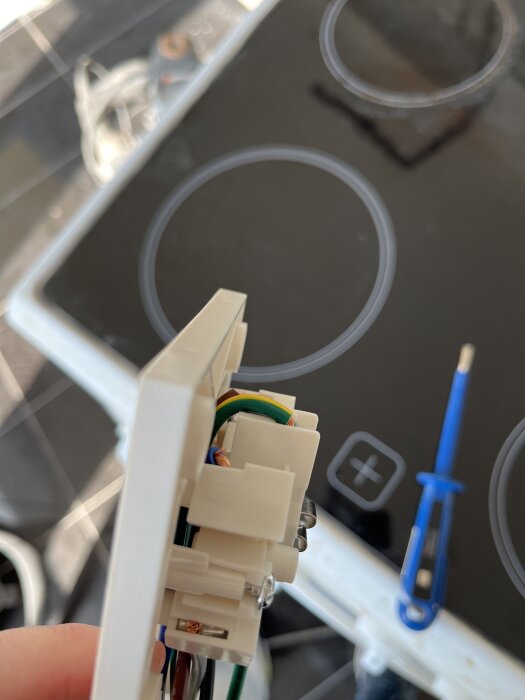 Närbild av en perilex-anslutning där det ser ut som två stift är avklippta. En spis med kokzoner ses i bakgrunden.