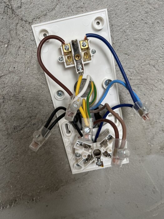 Elinstallation med flera kablar anslutna i kopplingsplatta mot vägg.