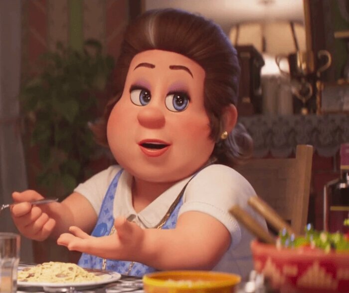Amiabel karaktär vid matbordet med pasta och gestikulerande hand.