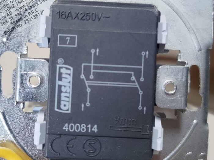 Svart strömbrytare med vit och elektrisk märkning, inklusive "16A 250V" och "400814". Fyra kopplingspunkter synliga.