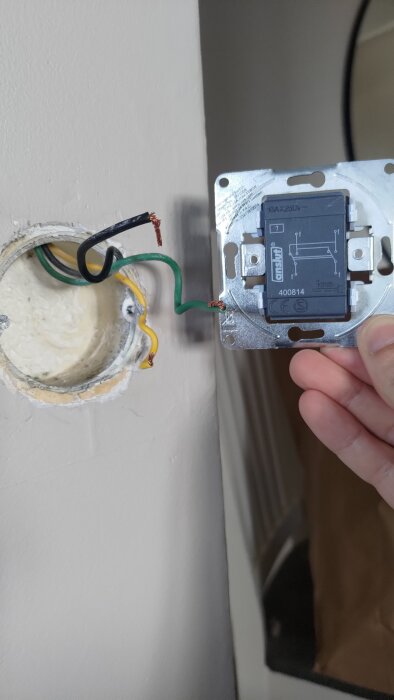 Ledningar och en lös strömbrytare monterad i väggen.