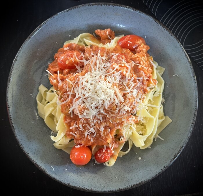 Färsk pasta med salsicciafärssås och riven parmesan på en tallrik.
