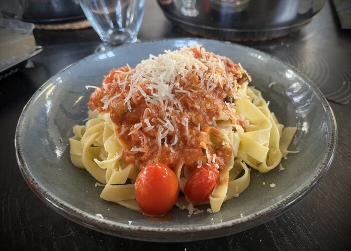 Färsk pasta med salsicciafärssås och riven parmesan på tallrik.