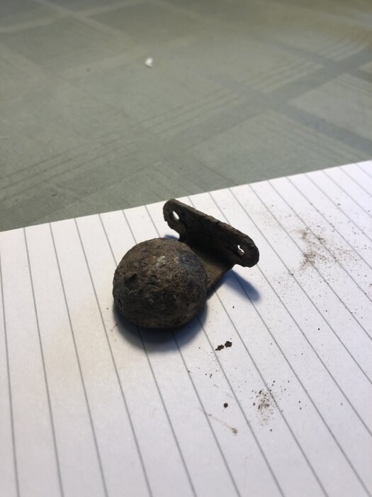 En liten, svagt magnetisk metallkomponent ligger på ett rutat papper.