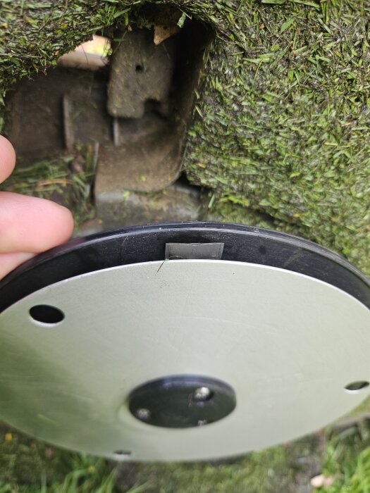 Närbild av undersidan på en robotgräsklippare med trasiga knivar.