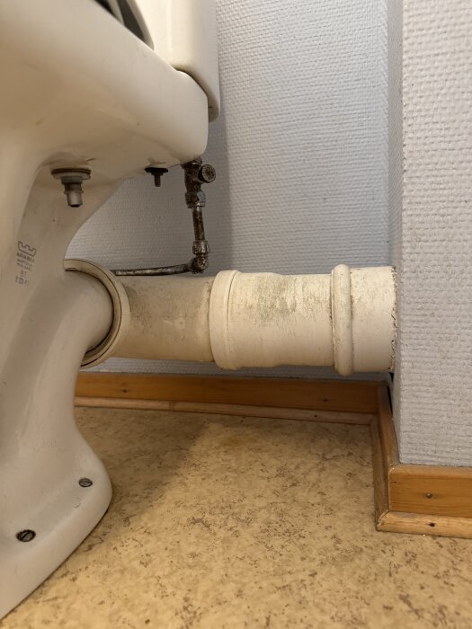 Toalettstol ansluten mot avloppsrör i nisch på gästtoalett, visar röranslutning och utrymme för möjlig installation av vägghängd toalett.